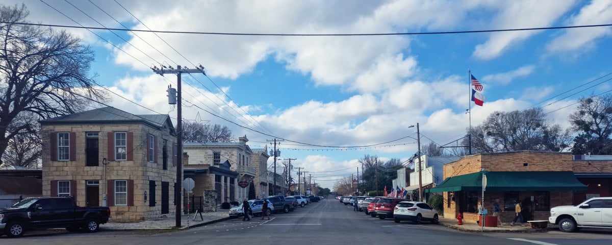 Parent and college-age student walking through a residential Austin neighborhood near UT campus, reviewing off-campus housing options