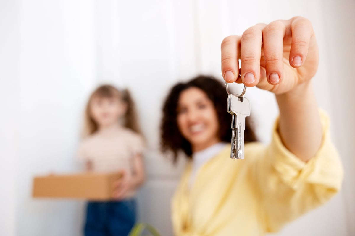 Parent and college-age student with house keys and moving boxes — evaluating ownership near Penn State University instead of paying rent